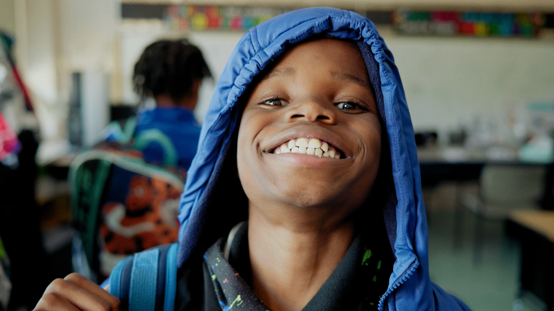 Youth participant smiling in a blue hooded jacket